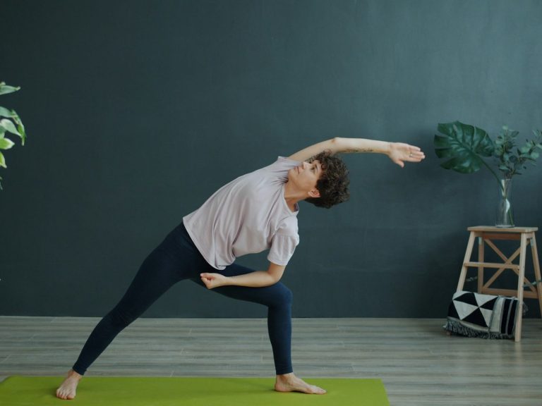 Menschliche Figur in Yogapose, gedehnt zur Seite, auf einer grünen Matte.