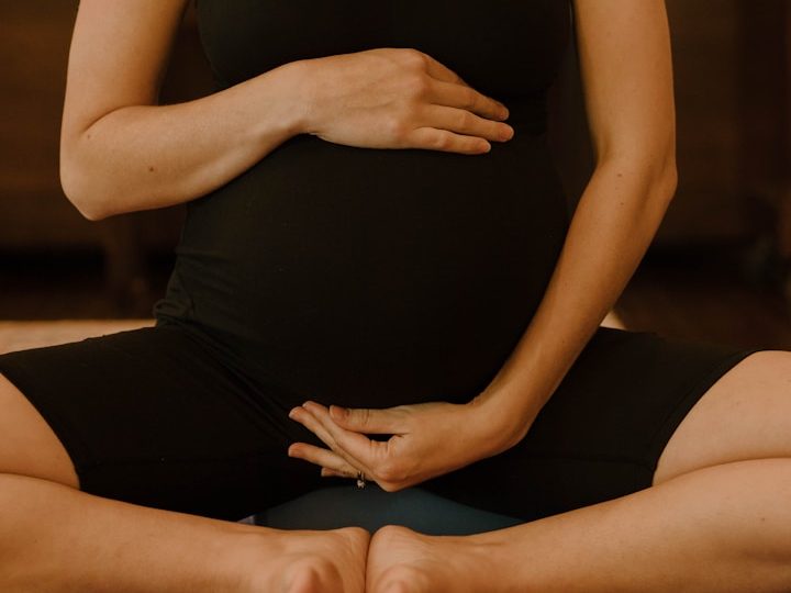 Schwangere meditiert im Schneidersitz vor einer malerischen Berghorizont bei Sonnenaufgang. Macht Yoga
