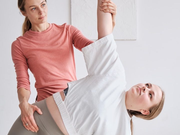 Eine Person unterstützt eine andere bei einer Dehnübung.