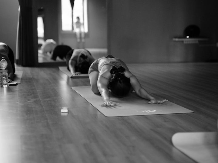 Person macht eine Dehnübung auf einer Yogamatte in einem Yoga Studio.