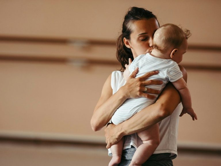 Eine Frau hält ein Baby in den Armen, während sie in einem Tanzstudio steht.
